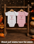 Cute Halloween onesie featuring an adorable ghost and “Ghouls Just Wanna Have Fun” design in pink and white baby bodysuits displayed on wooden hangers.