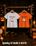Toddler Halloween shirts featuring Spooky Lil Dude ghost designs in white and orange, displayed in a festive Halloween setting with pumpkins and warm lights.